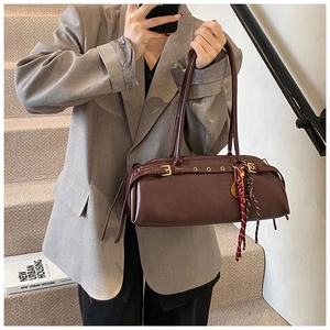 Gros plan du sac baguette marron rétro avec boucle dorée et foulard en soie rayé
