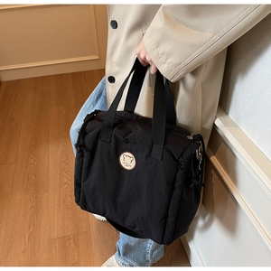 Close-up of black nylon tote bag with bear patch and durable metal zipper detail