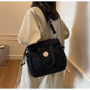 Dettaglio della borsa in nylon nero con lacci laterali e toppa rotonda con orso