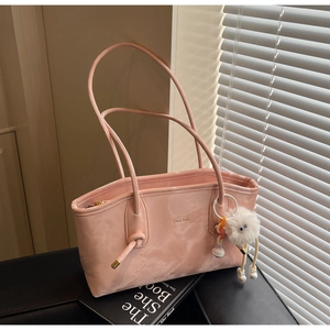 Detail of light pink leather tote bag with plush charm and printed branding logo