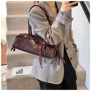 Détail du sac baguette vintage en cuir marron rouge foncé avec œillets métalliques