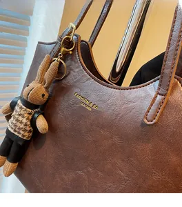 Close-up of brown pebbled leather tote bag with gold lettering and cute bunny pendant