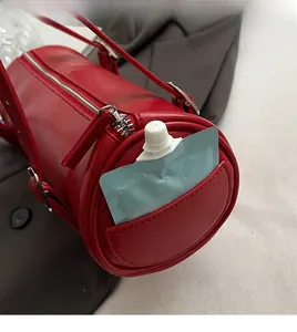 Detail of red cylindrical shoulder bag showing side pocket for small items storage