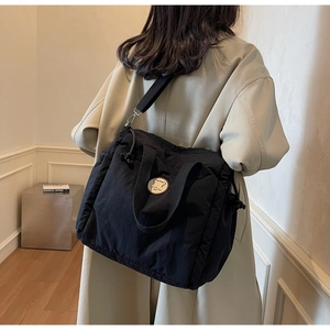 Detail of black canvas tote bag showing side drawstring design and wide shoulder strap