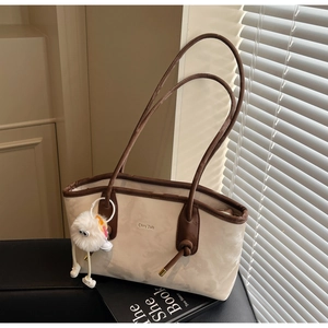 Detail of vintage beige tote bag with brown leather trim and plush monster charm