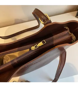 Detail of smooth metal zipper and golden hardware on a vintage brown tote bag