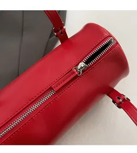 Detail view of smooth silver zipper closure and fine leather texture on red barrel bag