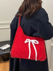 Red plush tote bag with a white knit bow accent and red leather shoulder strap