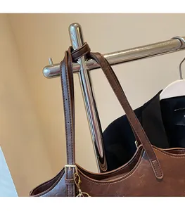 Detail of adjustable leather strap and golden metal buckle on a dark brown tote bag