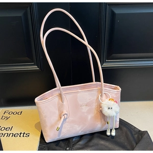 Detail of pink marble tote bag with unique knot handles and a white plush monster charm