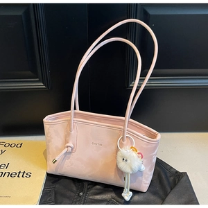 Pink matte leather tote bag detail with knotted shoulder strap and plush charm