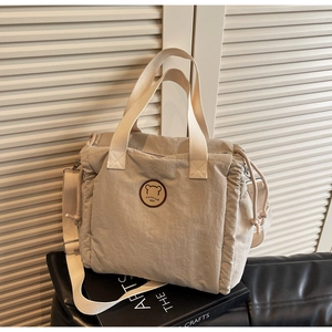 Detail of beige canvas tote bag showing drawstring closure and brown leather logo patch
