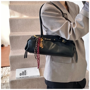 Détail du sac baguette noir avec œillets dorés et porte-clé raquette de tennis