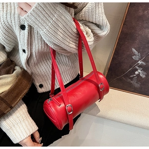 Close-up of a red cylinder shoulder bag with silver buckles styled with an autumn sweater