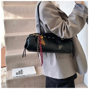 Détail du sac baguette en cuir noir avec œillets métalliques et charm de raquette de tennis