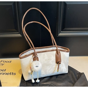 Detail of white marble print tote bag with brown leather straps and plush charm