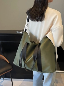Grand sac fourre-tout en nylon vert olive avec bandoulière lettrée porté par un mannequin
