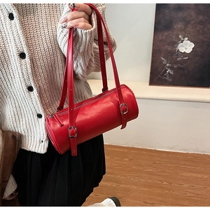Detailed macro view of the vibrant red cylindrical shoulder bag with silver hardware accents