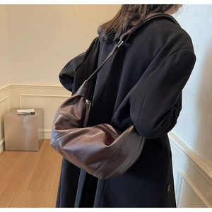 Deep brown pleated hobo bag shown on model in a stylish indoor setting with soft lighting