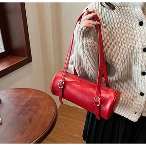 Detail of red cylindrical shoulder bag with glossy finish and silver metal buckle