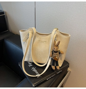 Detail of cream leather tote bag with fashion lettering and cute rabbit pendant