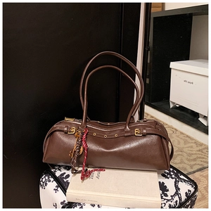 Gros plan d'un sac baguette vintage marron foncé avec boucle dorée et pendentif chic