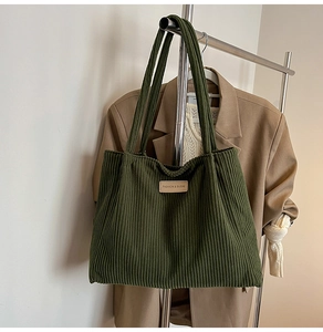 Detail of green corduroy tote bag with fashion label shown in a lifestyle outfit setting