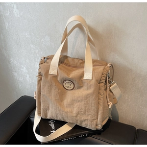 Detail of beige canvas tote bag showing fashion leather patch and side drawstring textures