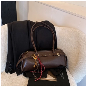 Détail d'un sac baguette vintage en cuir marron avec pendentif clé doré et sangles en métal