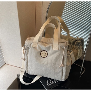 Detailed view of cream quilted tote bag with cute bear patch and adjustable strap