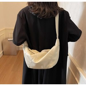 Minimalist beige crescent shoulder bag with soft pleats and metallic zipper detail