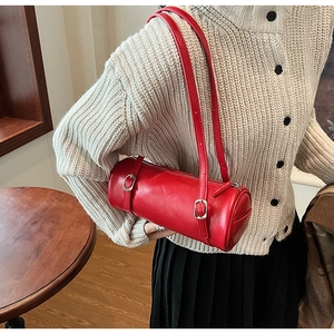 Close-up of vibrant red cylindrical leather shoulder bag with silver buckle and dual straps