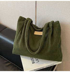 Detailed view of dark green corduroy tote bag with vintage leather patch and dual handles