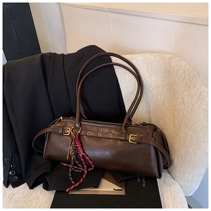 Détail d'un sac baguette marron foncé avec boucle métallique et breloque en corde tressée