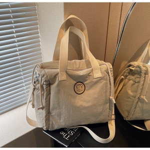 Detail of beige canvas tote bag showing drawstring design and cartoon bear patch