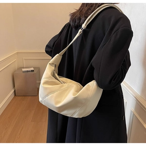 Close-up of cream half-moon hobo bag with diagonal stitching and lychee leather texture