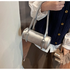 Close-up of metallic silver cylindrical barrel shoulder bag with adjustable buckle strap