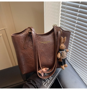 Detail of vintage brown tote bag with leather texture and cute rabbit charm