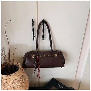 Détail du sac baguette marron foncé avec œillets métalliques et cordon tressé coloré