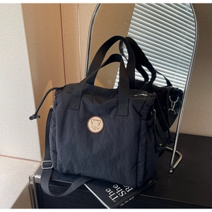 Detail of black canvas tote bag showing the round bear logo and drawstring side features