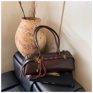 Détail du sac cylindre vintage marron foncé avec boucles dorées et décor de foulard