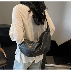 Rear view of a model wearing a black lychee texture half-moon bag with wide shoulder straps