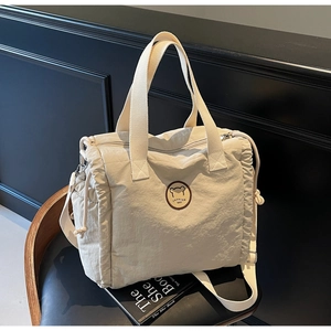 Detailed view of cream canvas tote bag featuring adjustable strap and side drawstrings