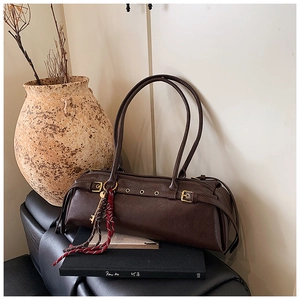 Détail du sac baguette vintage marron foncé avec boucles en métal et pompon coloré