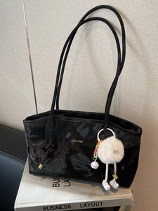 Glossy black wrinkled leather tote bag with gold logo and plush monster charm decoration