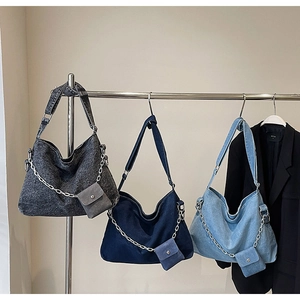 Three denim tote bags in grey and blue with metal chains and mini pouches shown hanging