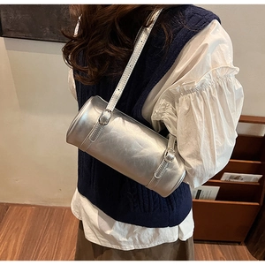 Detail of silver metallic cylinder shoulder bag with buckled straps and pleated texture