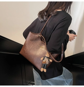 Close-up of vintage brown tote bag texture with gold stamp and plush bunny charm