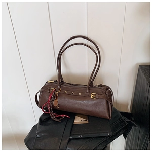 Détail d'un sac baguette cylindrique marron vintage avec breloque raquette et sangle sport
