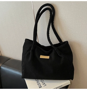 Close-up of black corduroy tote bag with vertical texture and branded fashion label